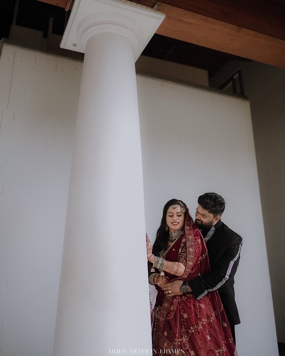 Newlyweds sharing a quiet embrace beside a white column